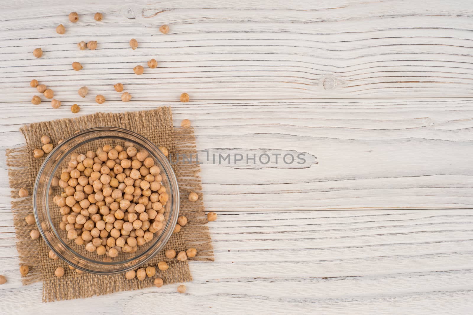 Chickpeas in a glass bowl on the old wooden table. Top view.