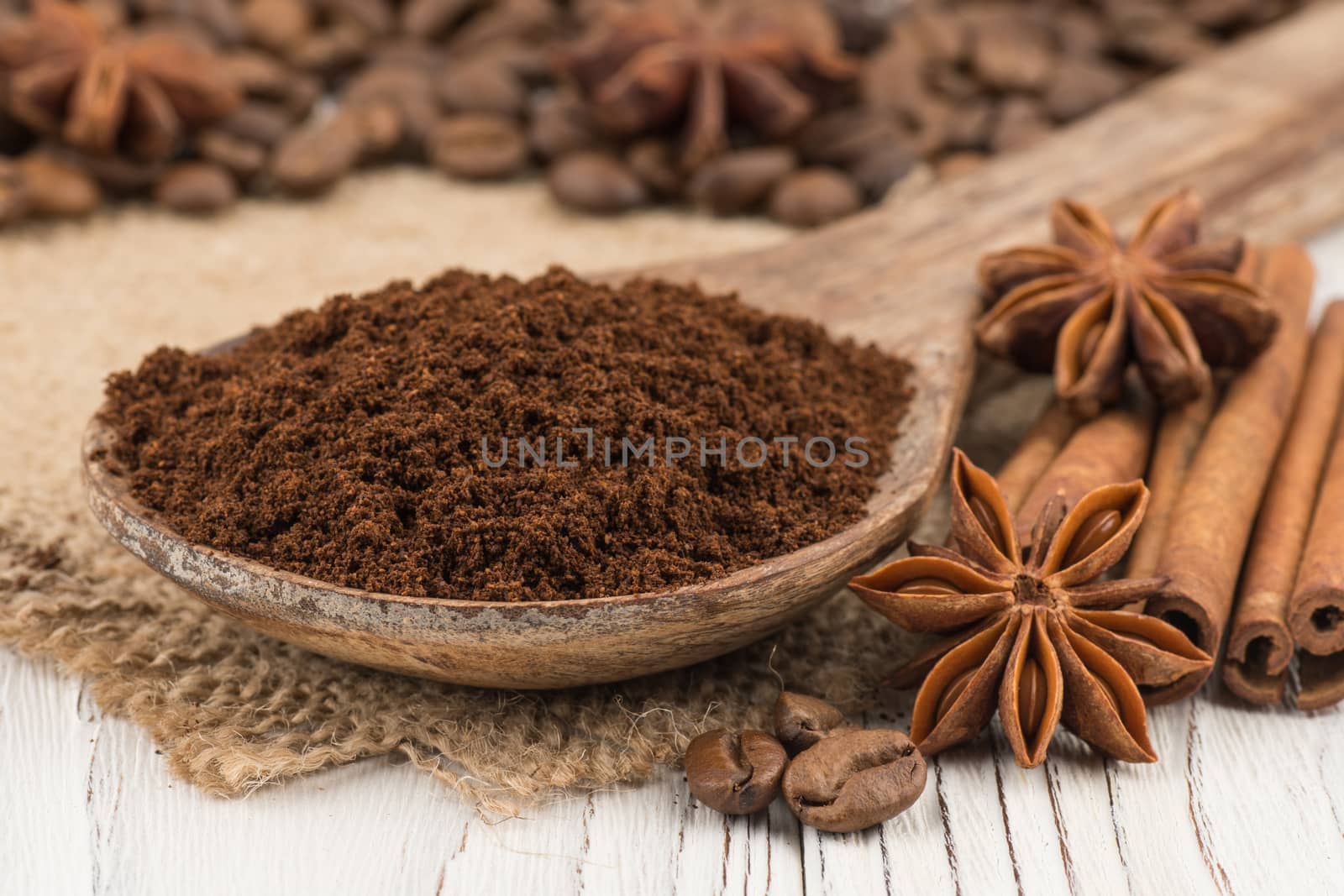 Ground coffee in a wooden spoon on  old white wooden table. Selective focus.