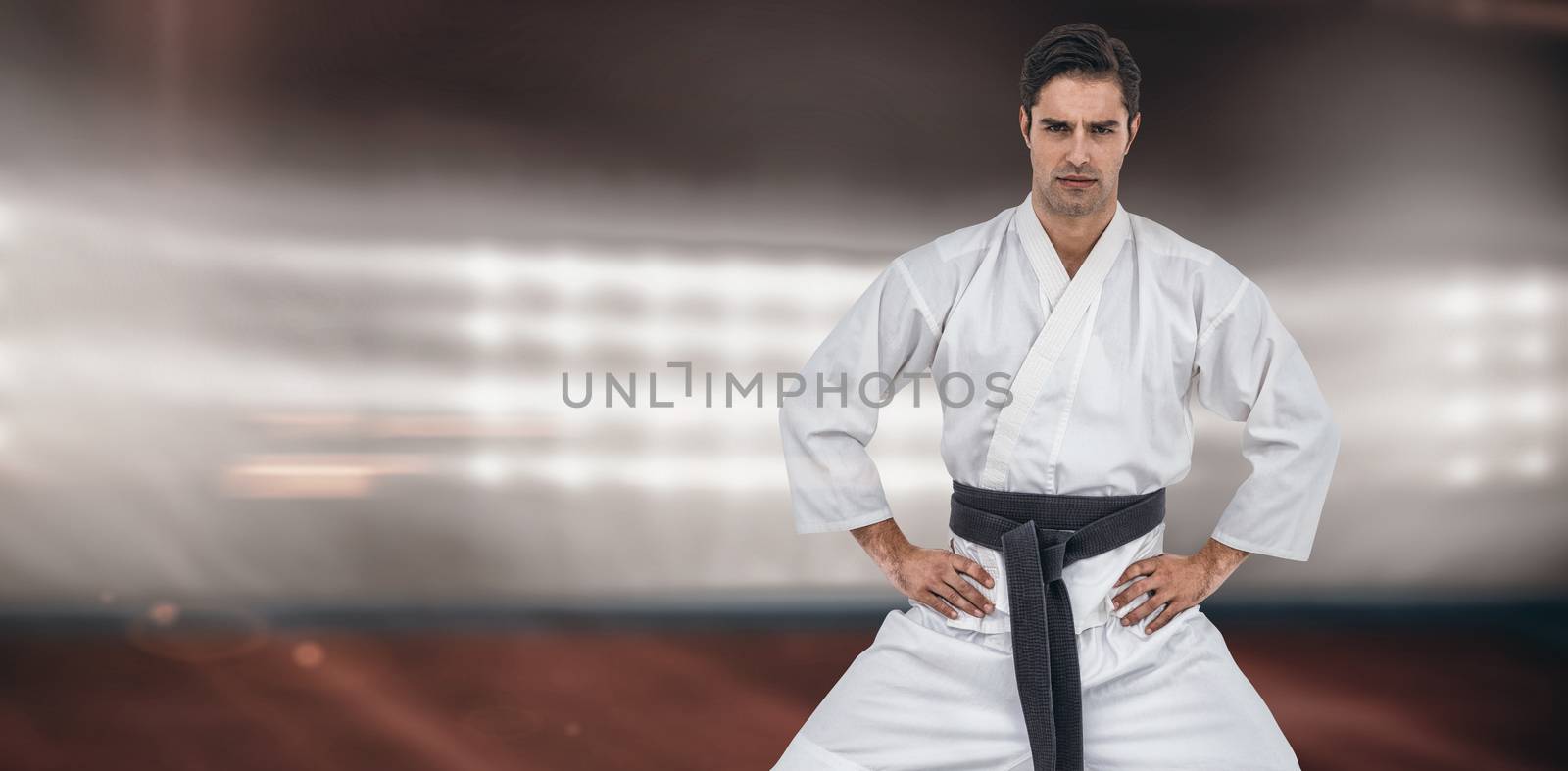 Portrait of fighter posing on white background against composite image of playing field indoor