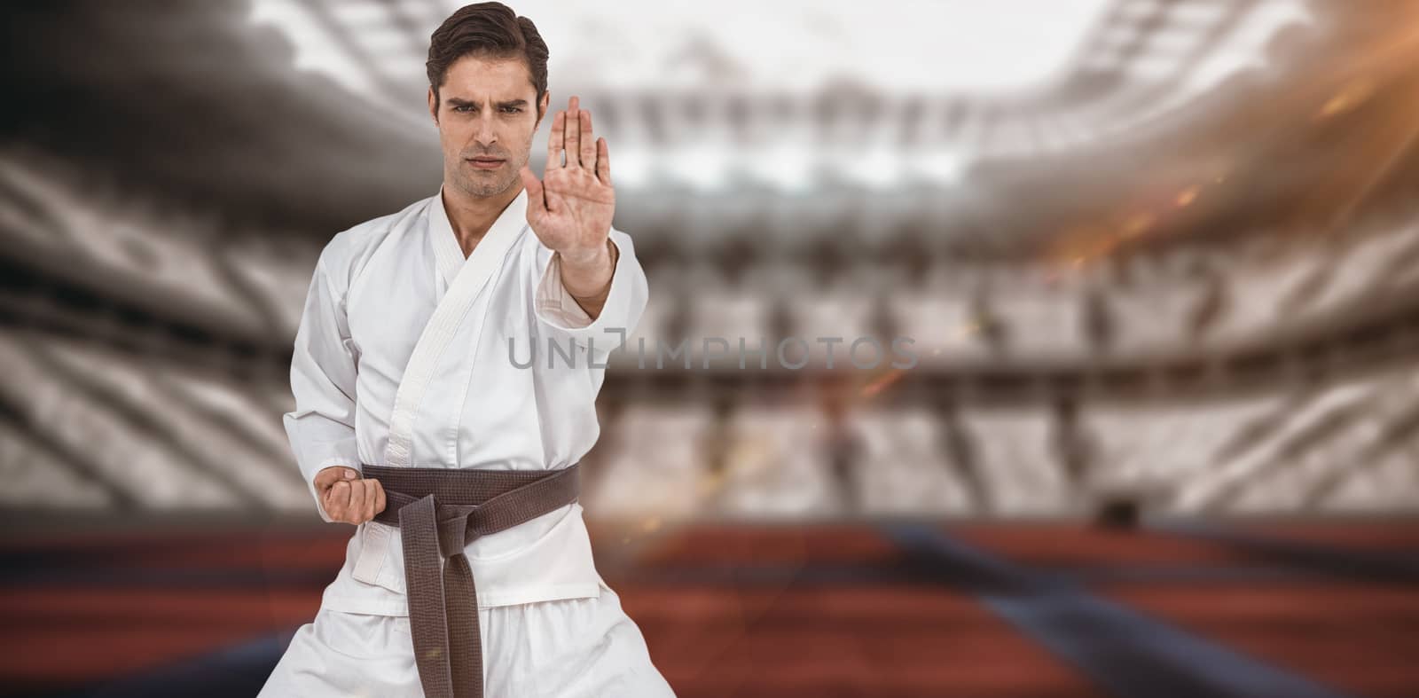 Portrait of fighter performing karate stance against digitally generated image of stadium