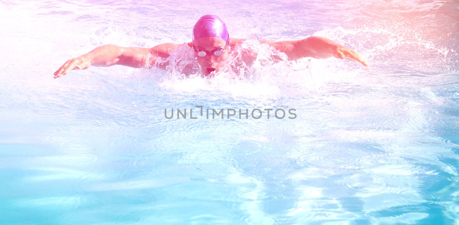 Fit swimmer doing the butterfly stroke in the swimming pool on a sunny day