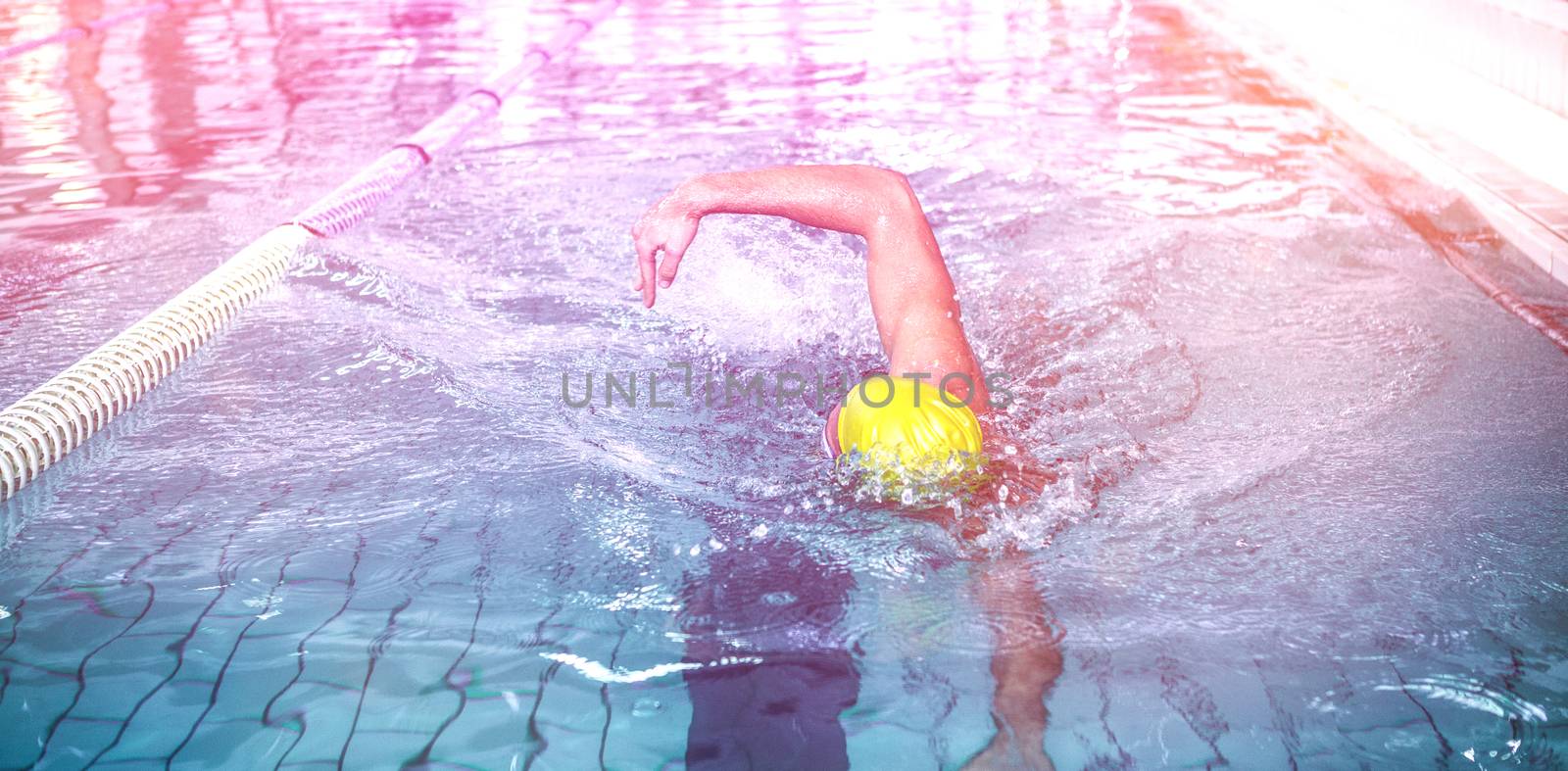Fit man swimming with swimming hat in swimming pool