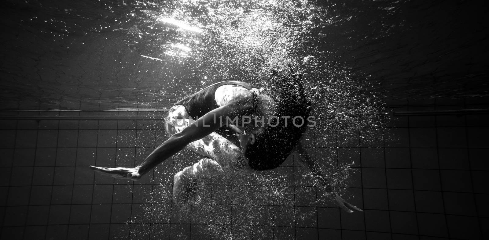 Athletic swimmer doing a somersault underwater in the swimming pool at the leisure centre