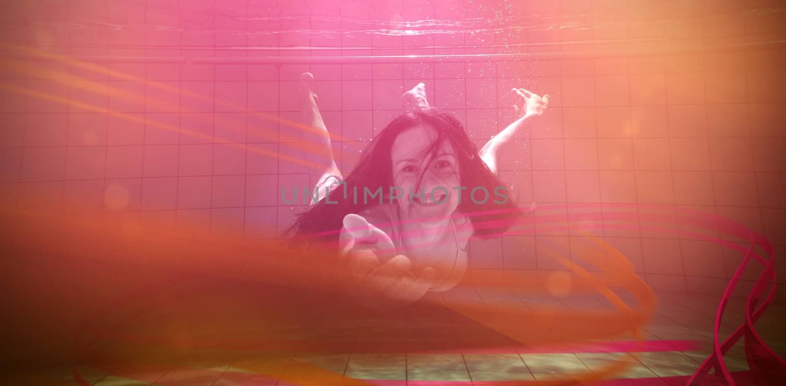 Pretty brunette smiling and offering her hand underwater in the swimming pool at the leisure centre