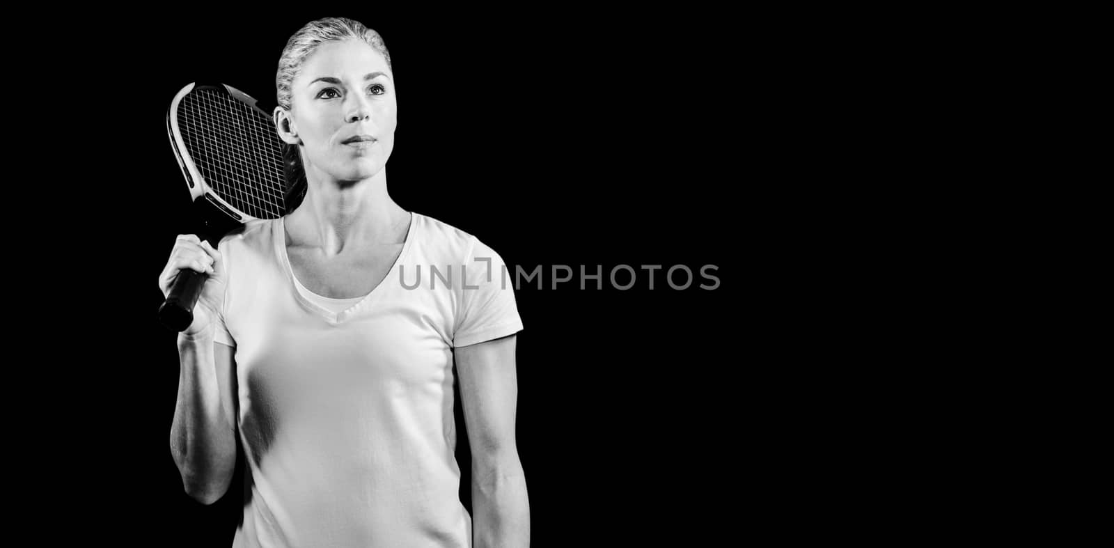 Female tennis player posing with racket on black background