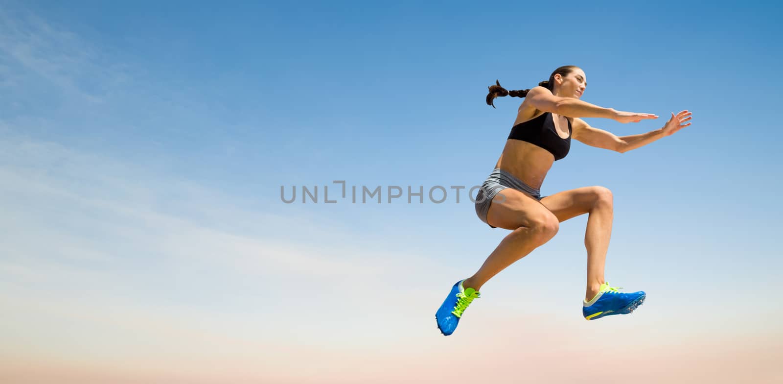 Sporty woman jumping against scenic view of blue sky