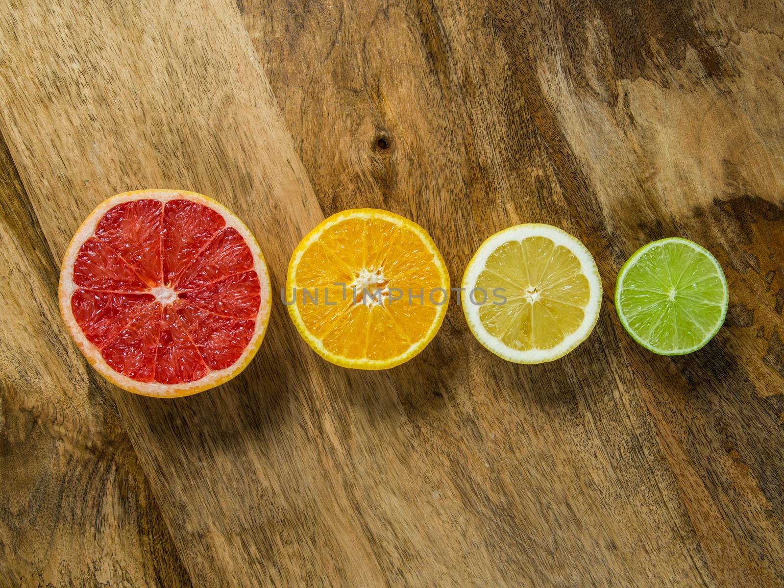 Photo of a lime, lemon, orange, and grapefruit, cut and arranged in a row.
