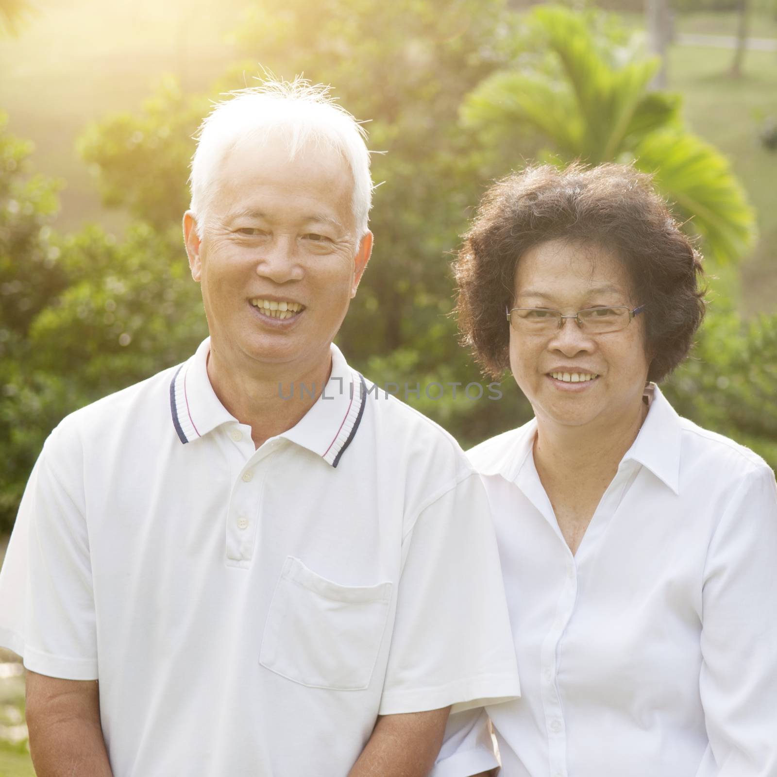 Portrait of healthy Asian seniors retiree couple having good time at outdoor nature park, morning beautiful sunlight background.