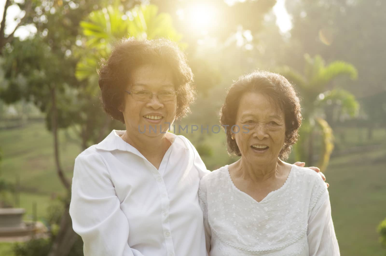 Portrait of healthy Asian seniors mother and daughter relaxing at outdoor nature park, morning beautiful sunlight background.