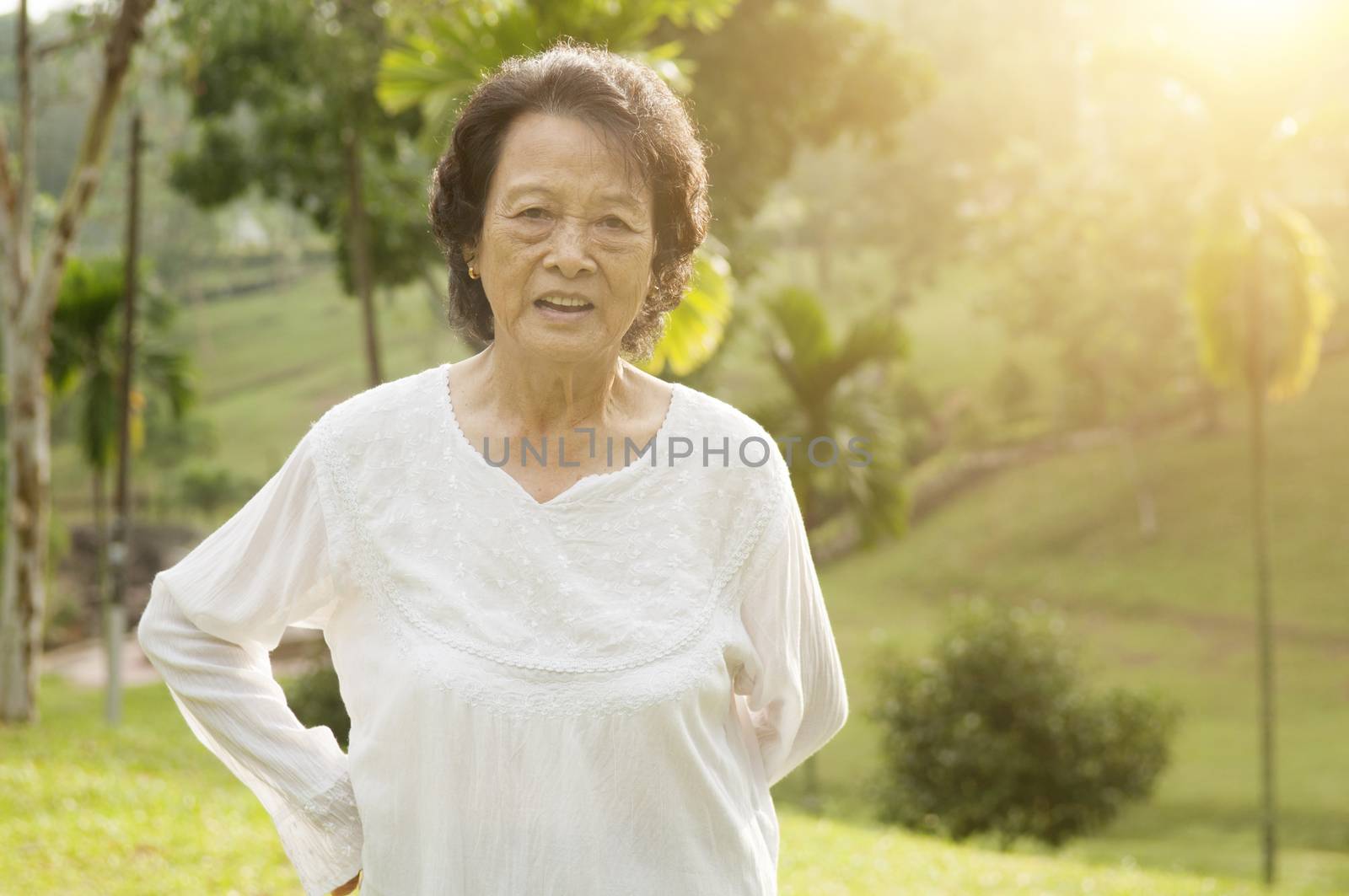 Portrait of healthy happy Asian senior woman doing morning workout at outdoor nature park, beautiful sunlight background.