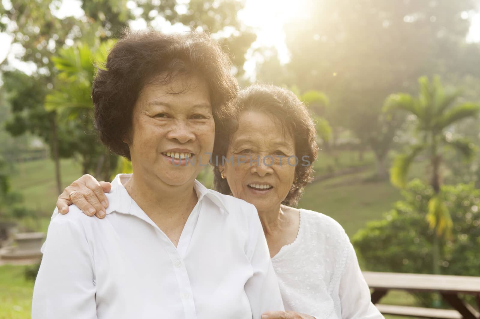 Portrait of healthy Asian seniors mother and daughter sitting at outdoor nature park, morning beautiful sunlight background.
