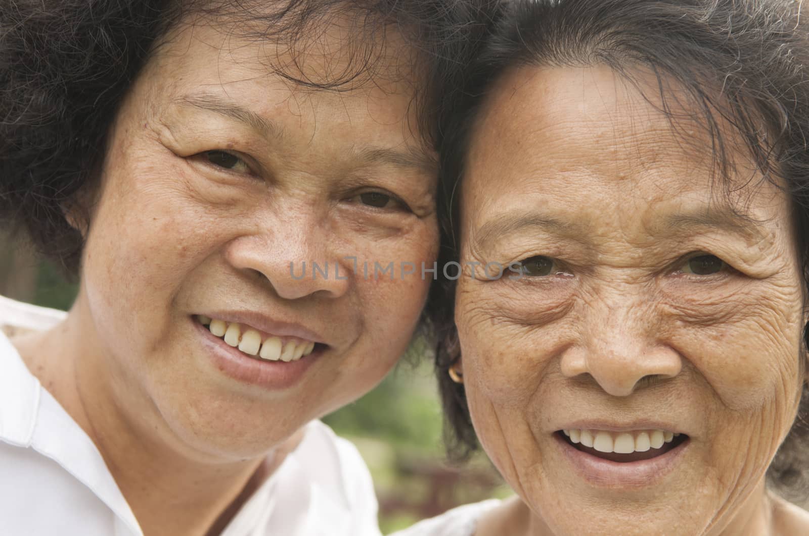 Portrait of healthy happy Asian seniors mother and daughter laughing at outdoor nature park, morning beautiful sunlight background.