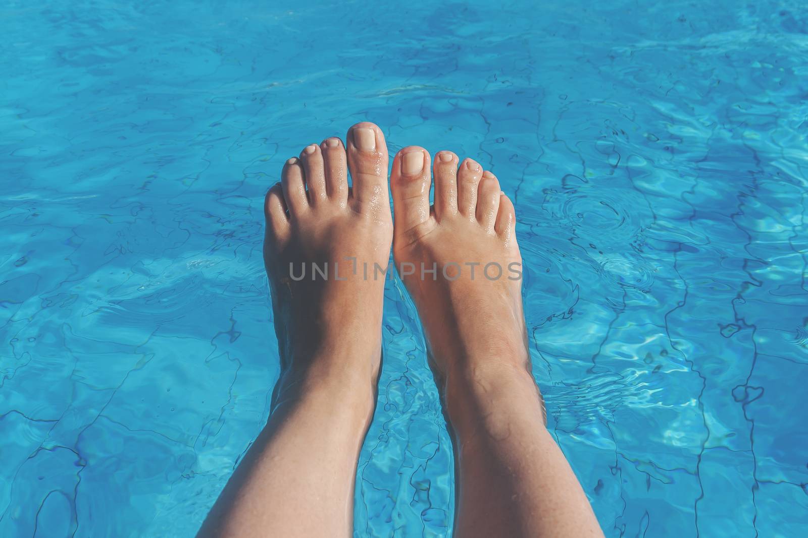 naked female legs on a background of blue water.