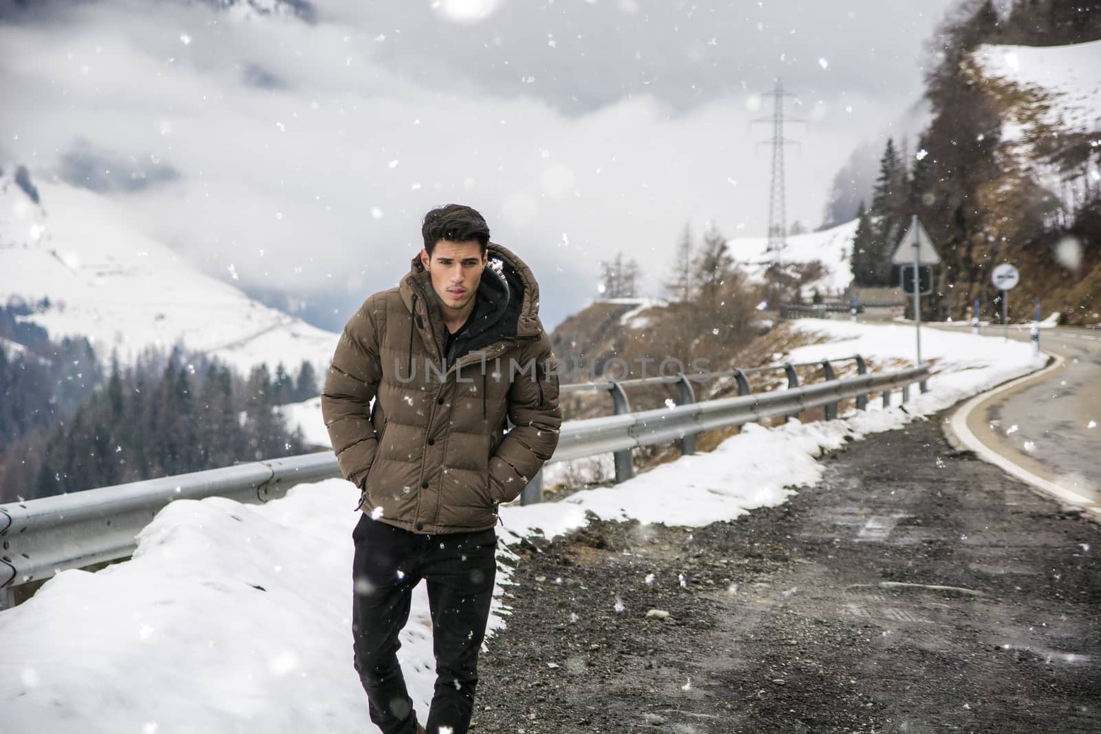 Young man walking on roadside under the snow by artofphoto