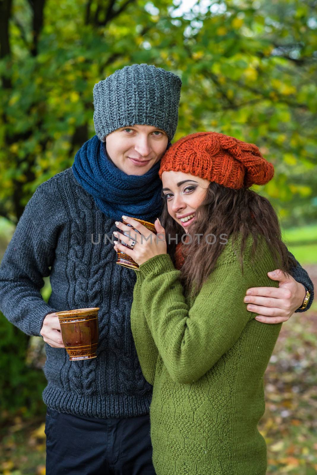 young couple in love with a cup of coffee in the autumn garden