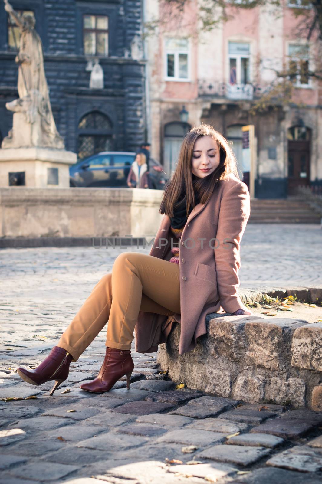 pretty girl sits on a rock in the city in the morning