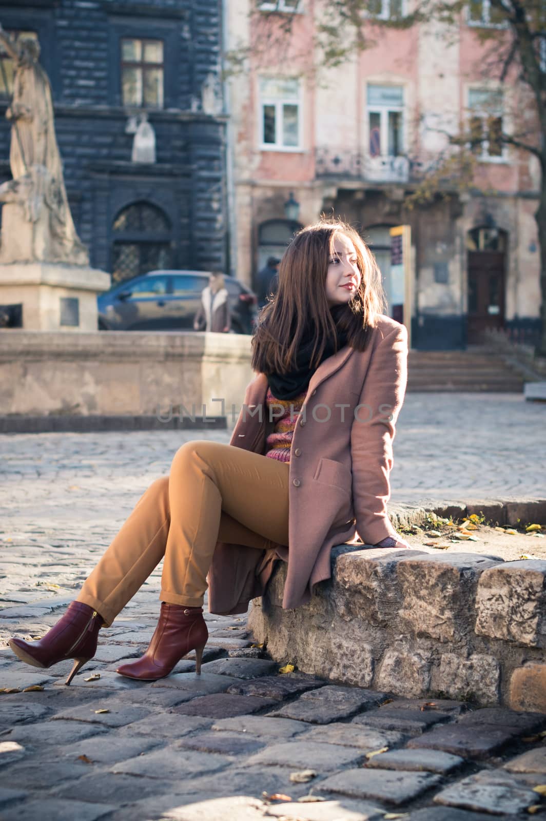 pretty girl sits on a rock in the city in the morning