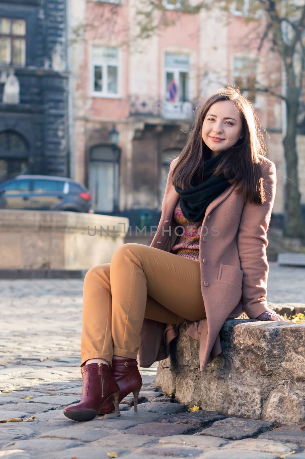 pretty girl sits on a rock in the city in the morning