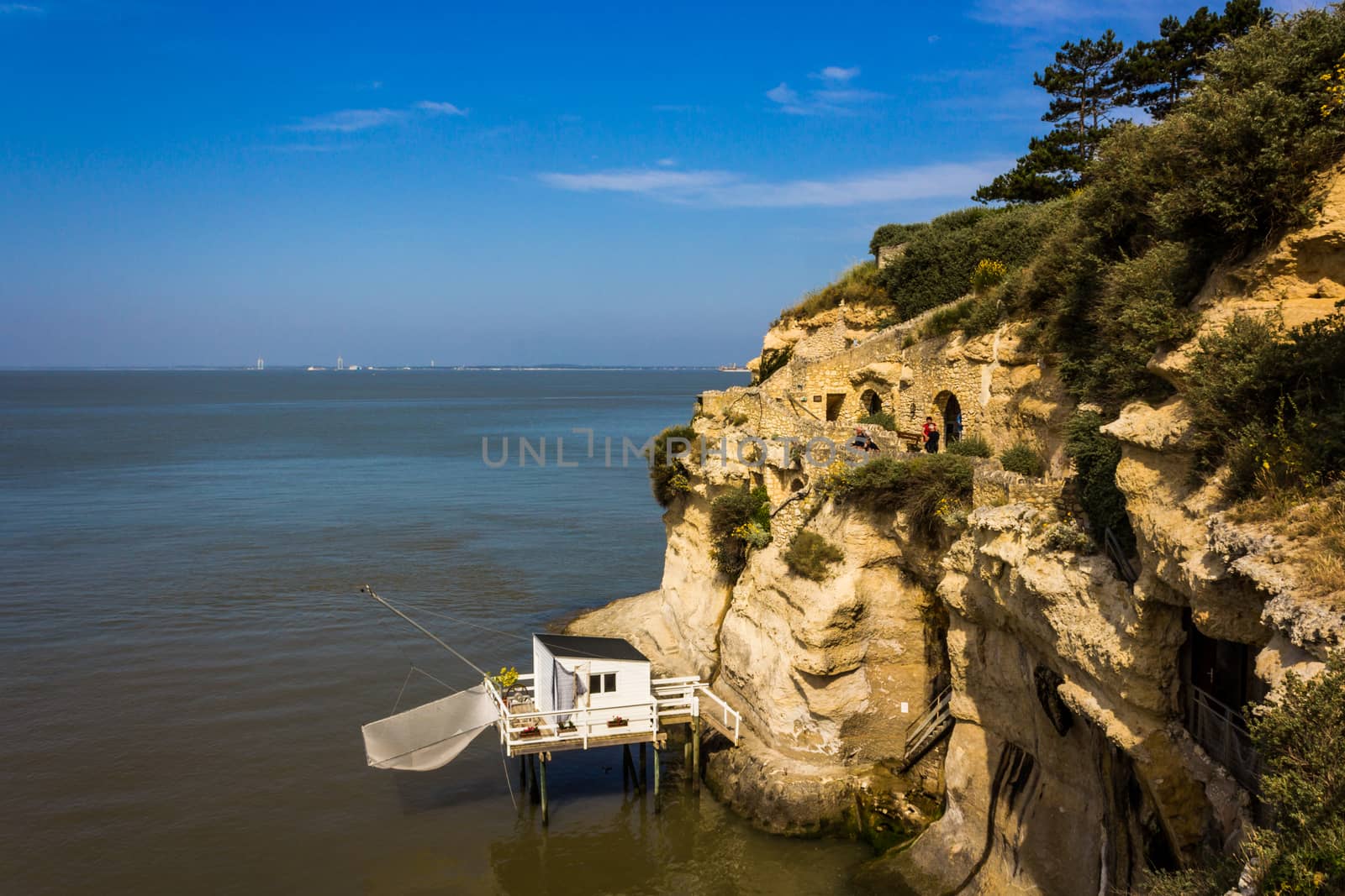 A white fishing hut next to some old walkways that cut through the cliffs