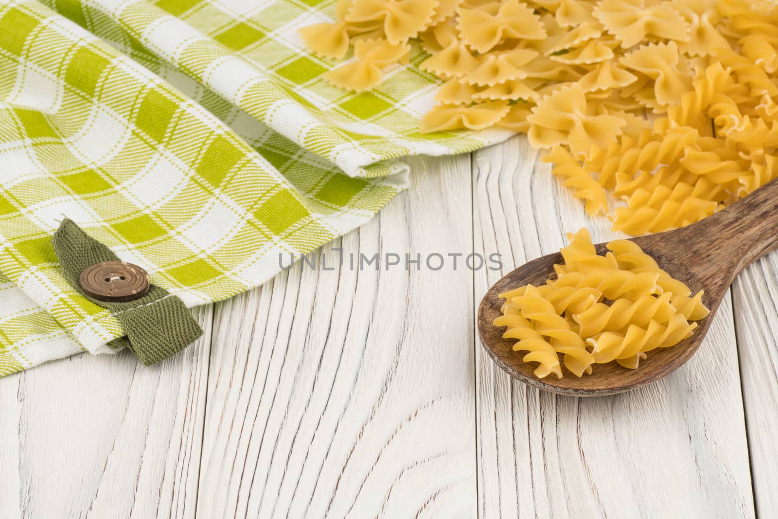 Pasta in a wooden spoon on old wooden table. Selective focus.