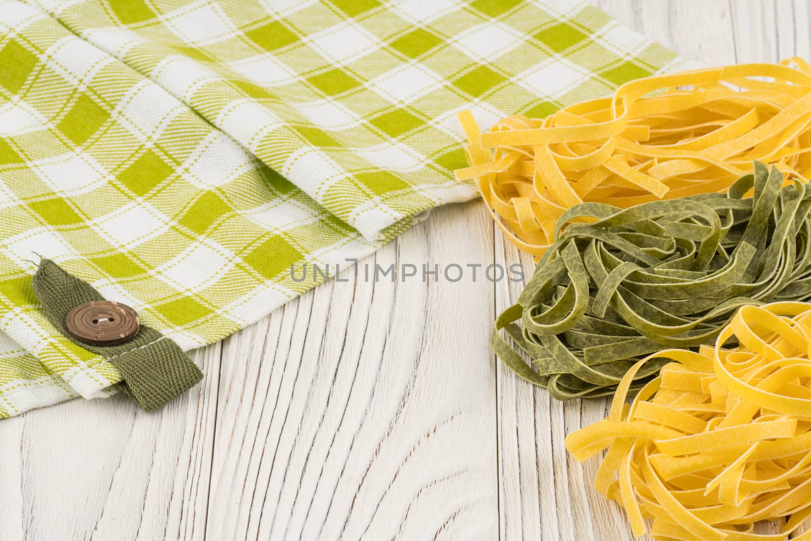 Raw green and yellow pasta on an old white wooden table.  by DGolbay