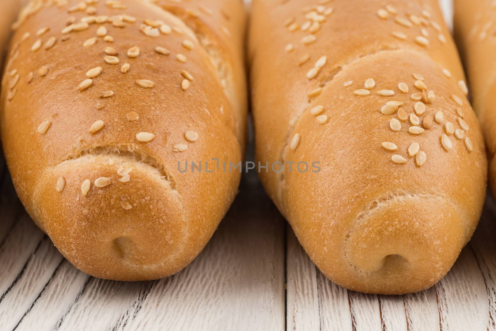 Bun with sesame seeds on old white wooden table. Selective focus.