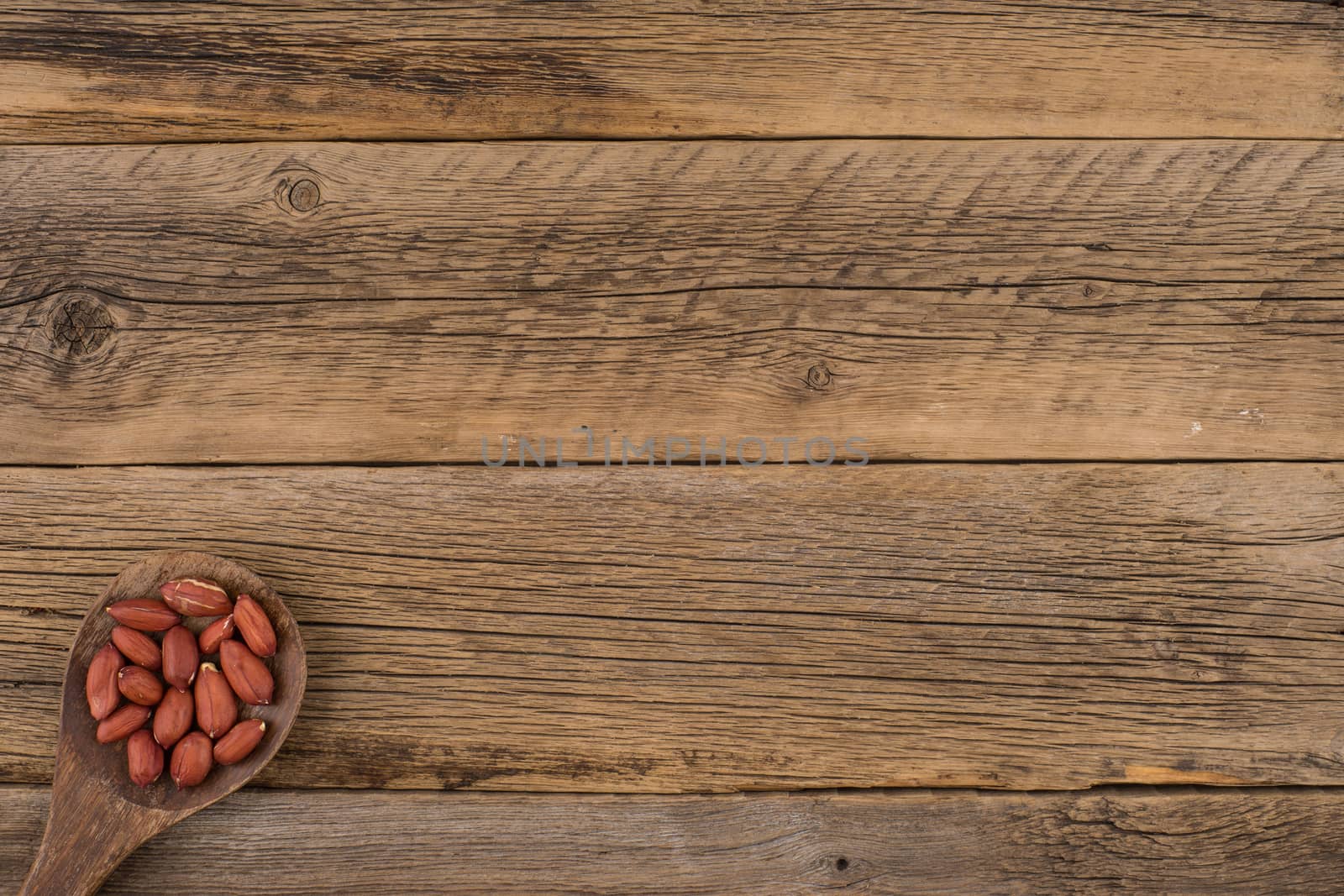 Peanuts in wooden spoon on old wooden background.  by DGolbay