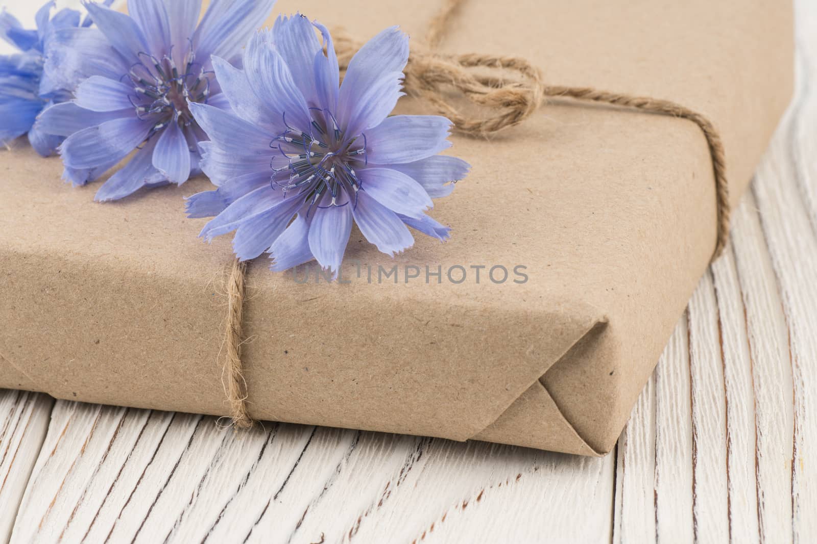 Gift box with a field flower on a white wooden table. Selective focus.