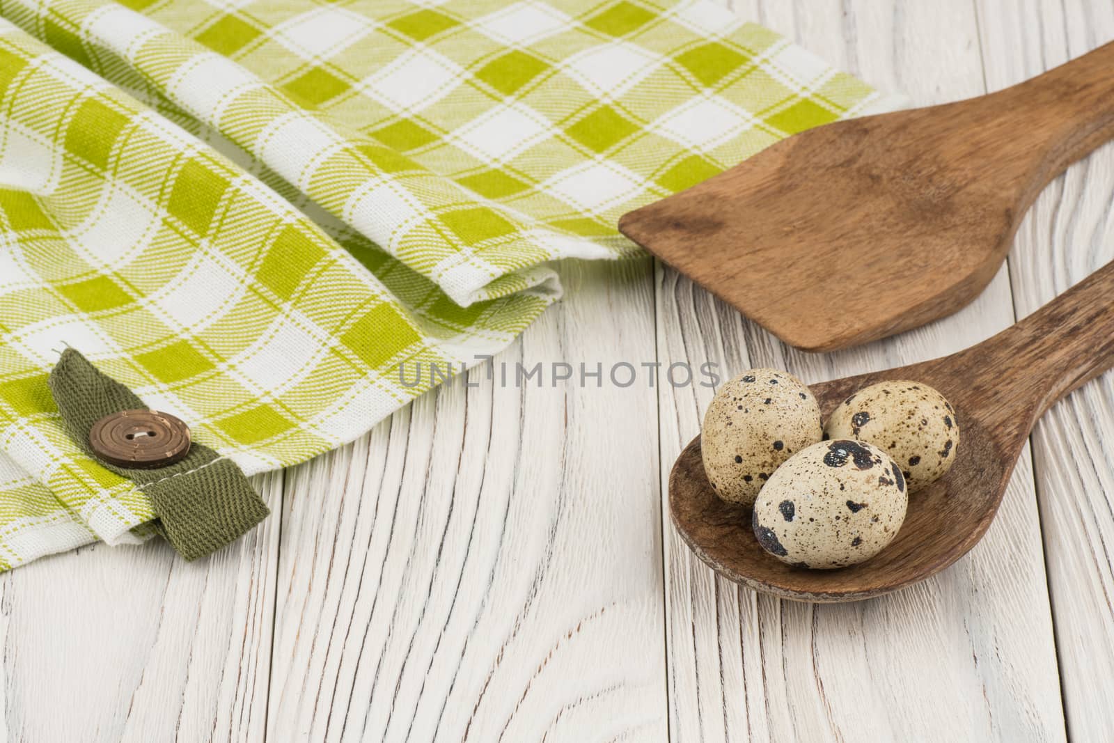 Quail eggs in a wooden spoon and an old wooden table. Selective focus.