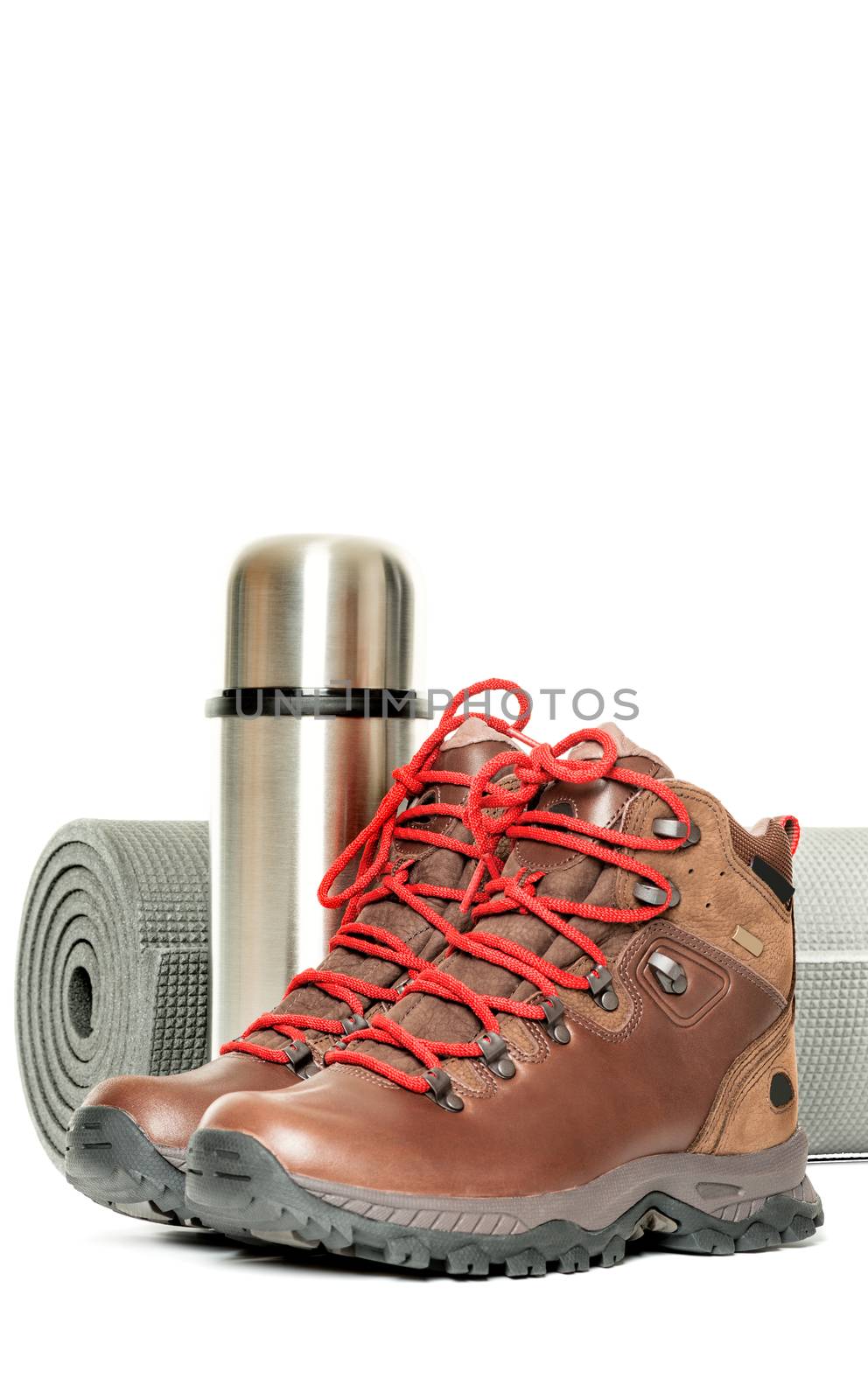 Hiker equipment: pair of mountain boots, thermo flask and sleeping mat on white background