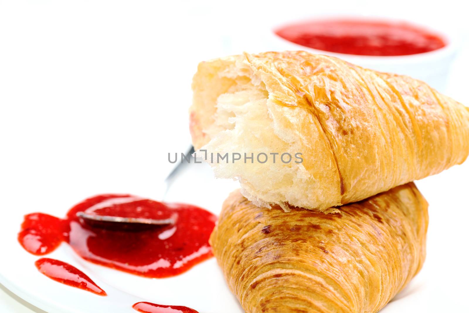 Croissant and jam on white plate close up