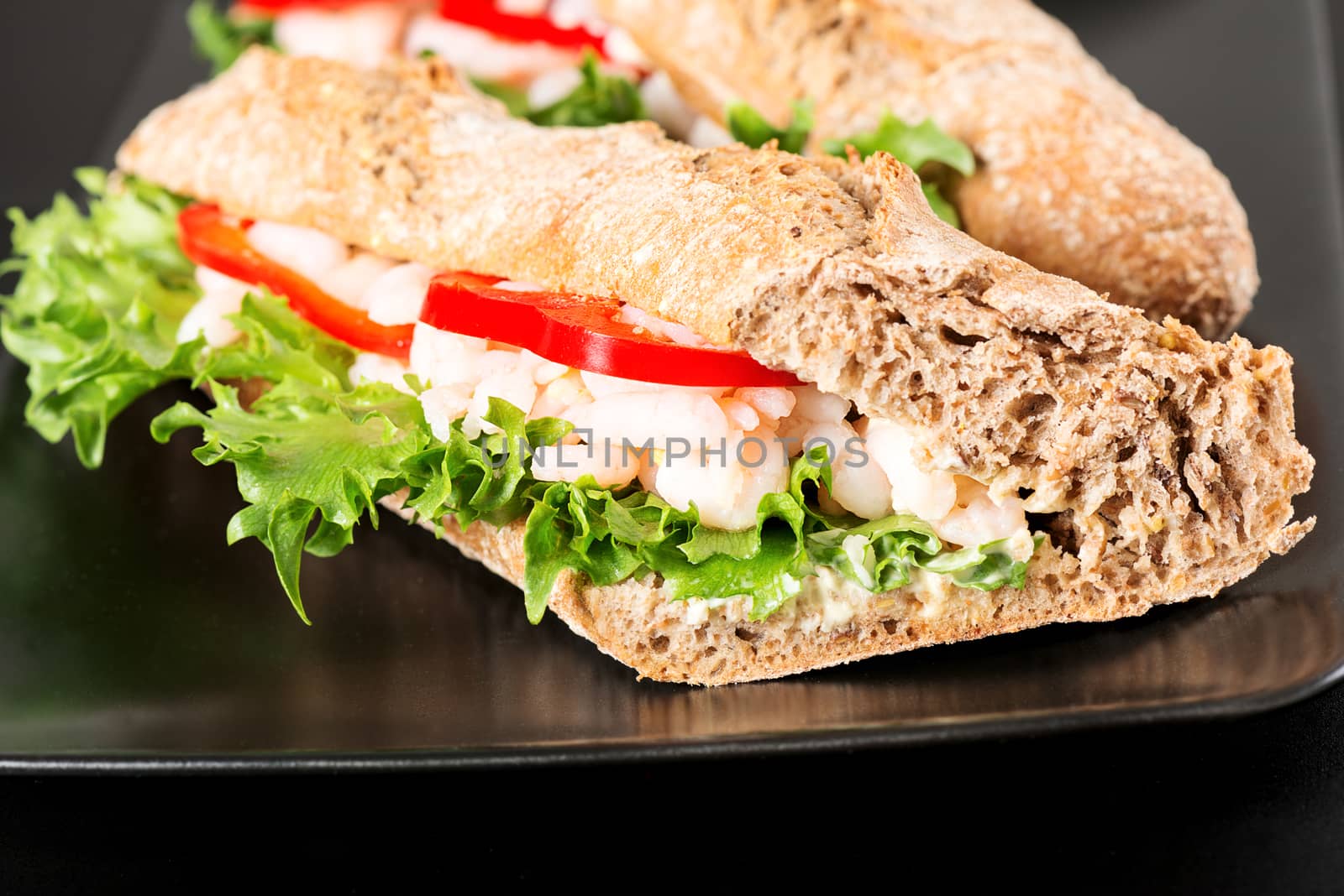 Prawn sandwich on black plate. Studio shot