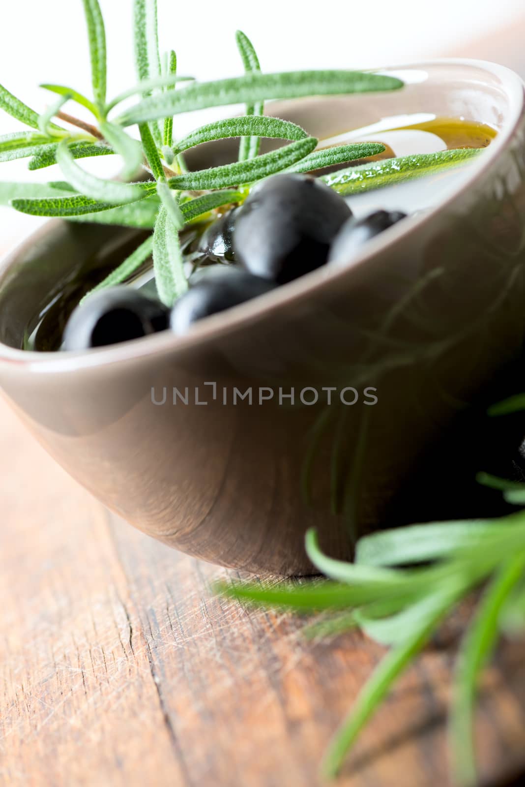 Black olives in clay bowl and rosemary set