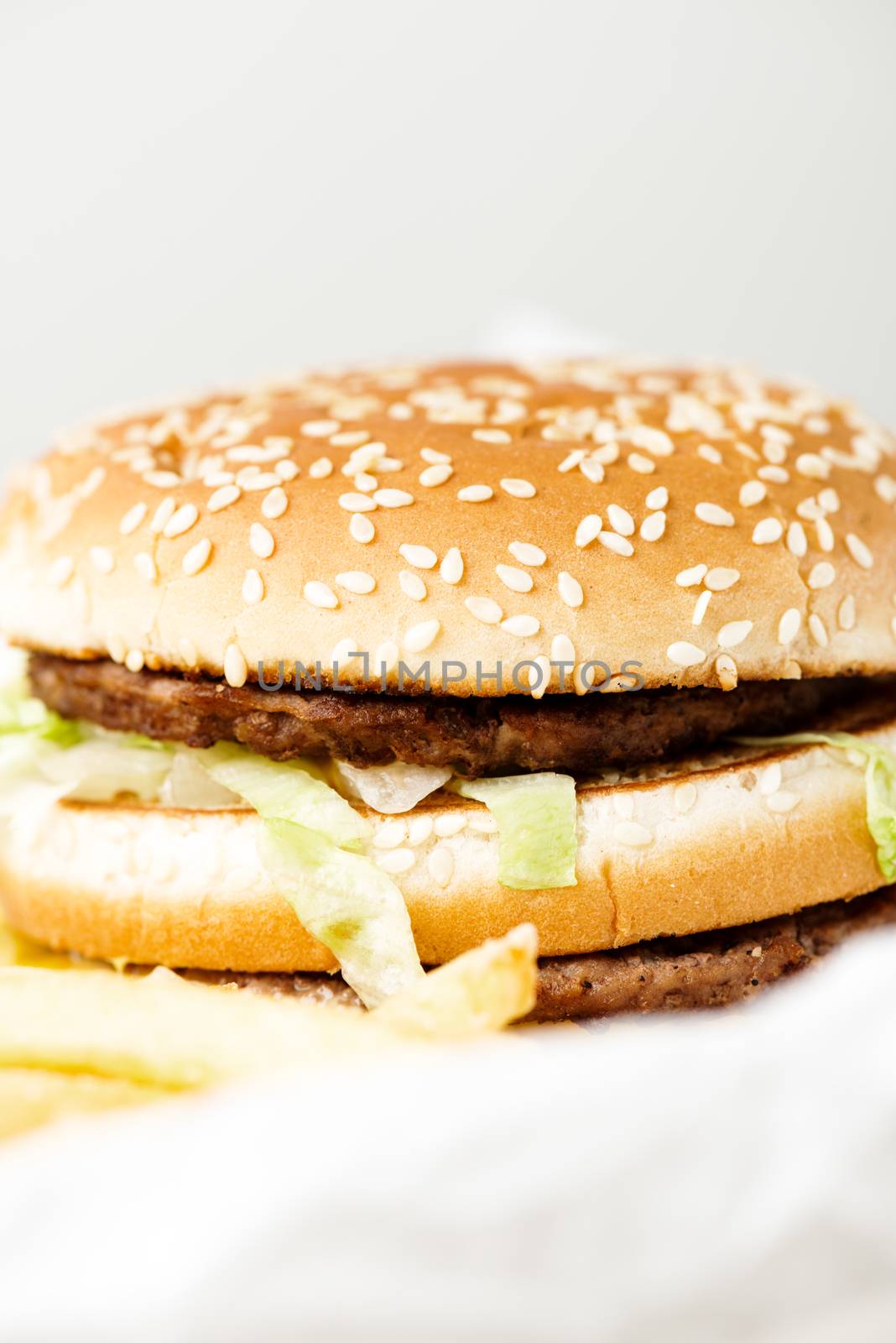 Double burger with french fries on white paper