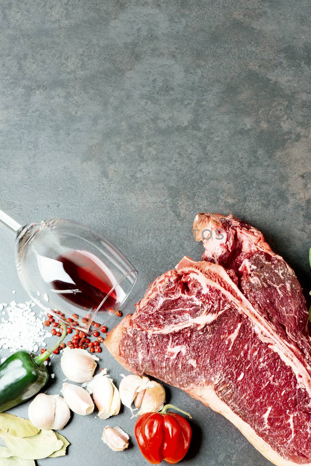 Raw aged steak and seasoning on dark background by Nanisimova