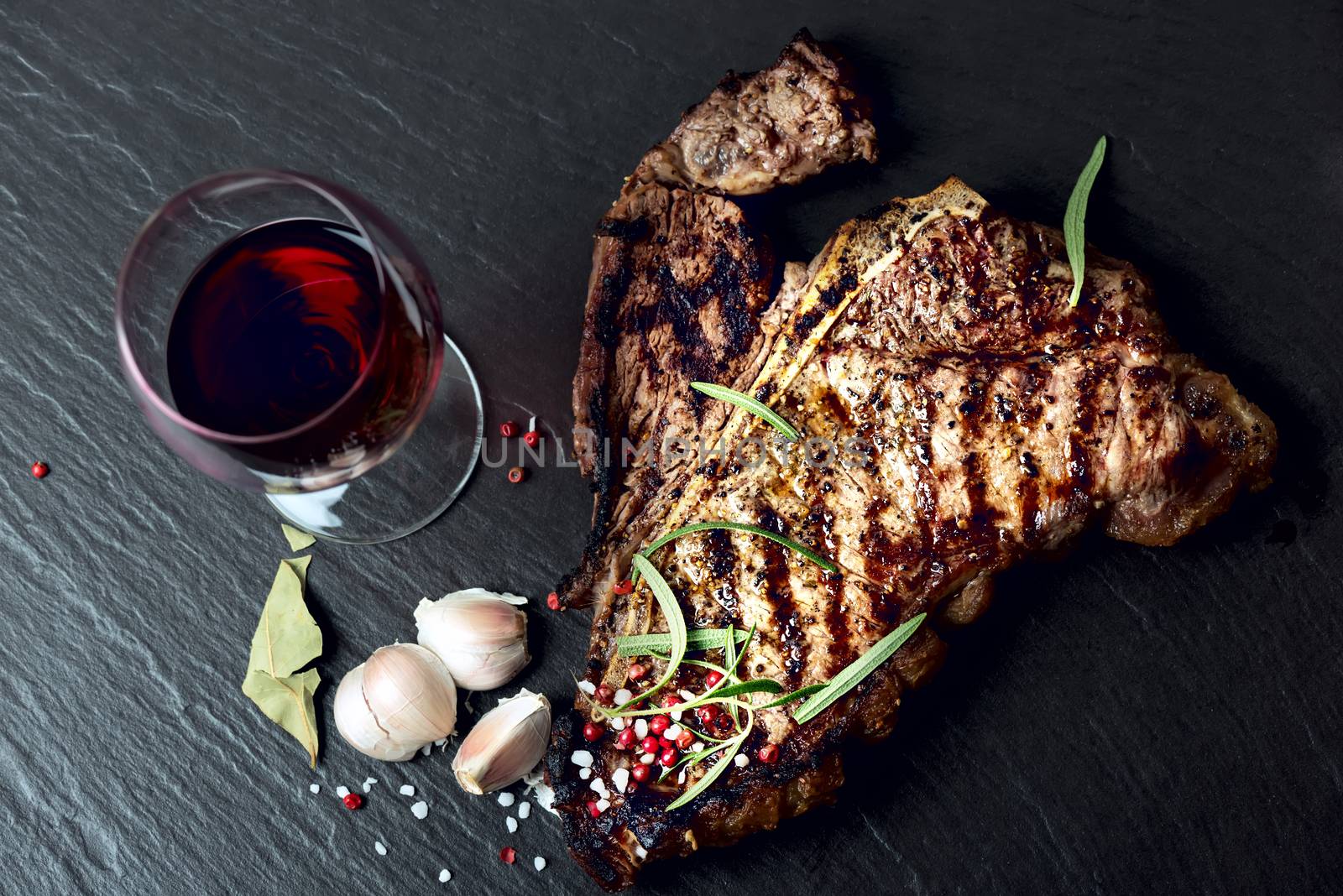 Steak with spices and glass of red wine on stone