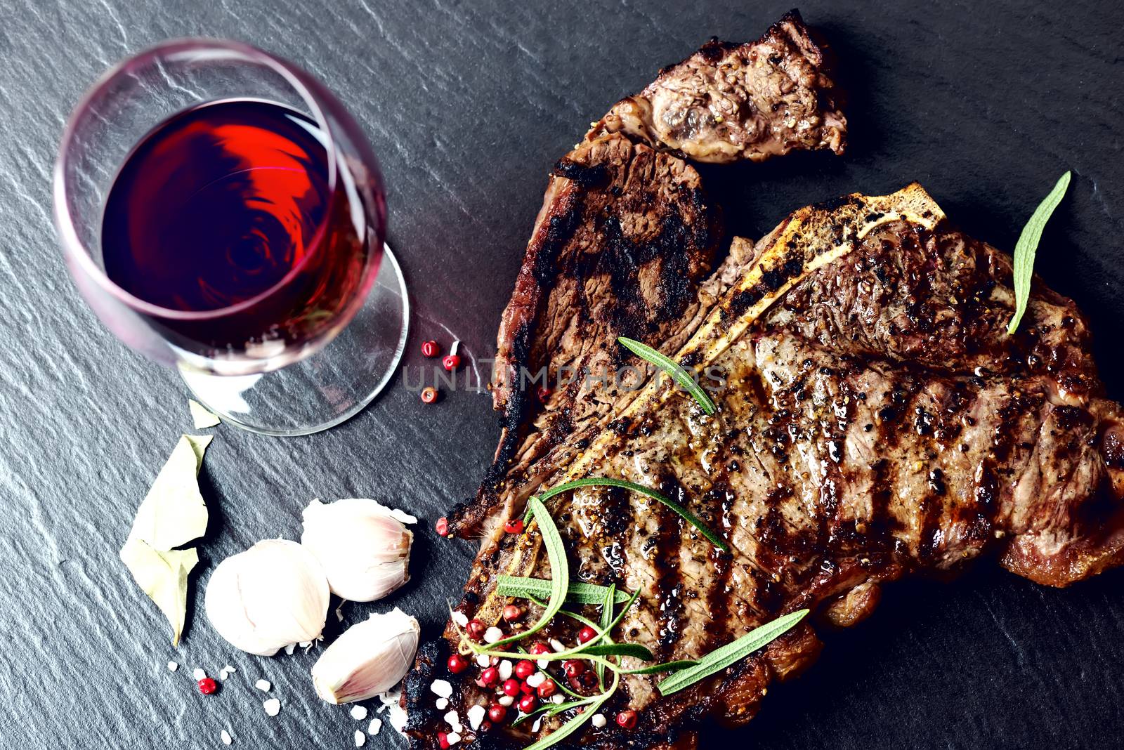 Steak with spices and glass of red wine on stone