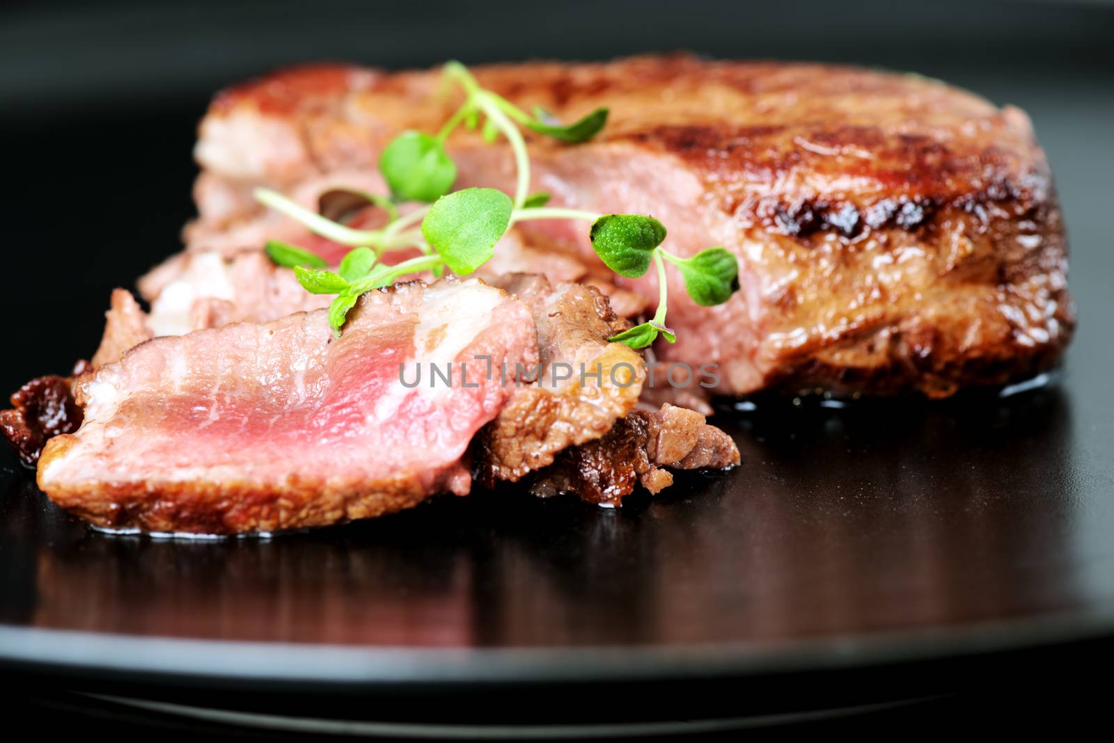 Delicious beef steak on a black plate, close-up