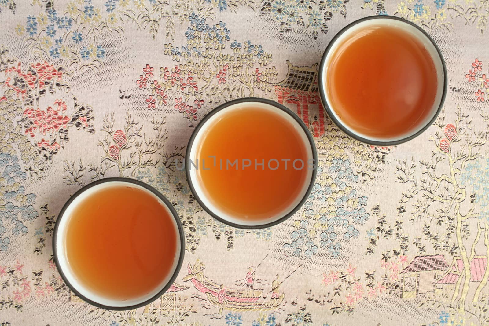three cup with tea on a beautiful tablecloth overhead shot close to  
