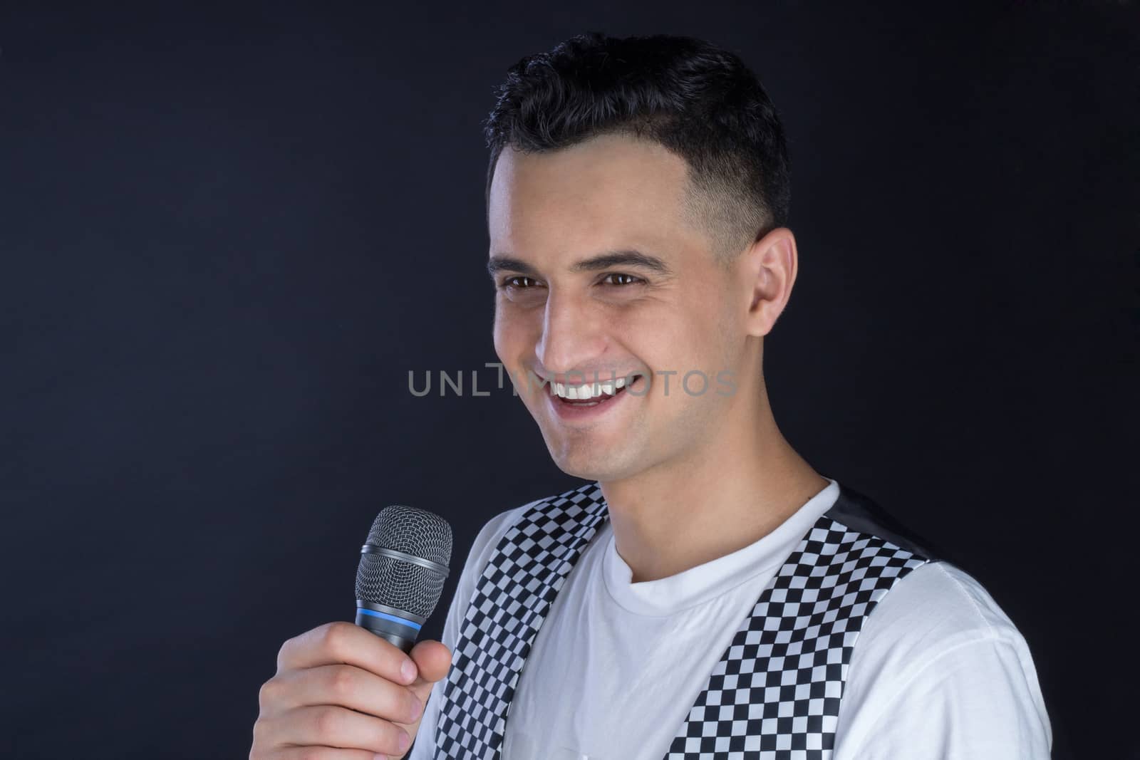 Young black-haired man dressed in black and white performs singing to microphone