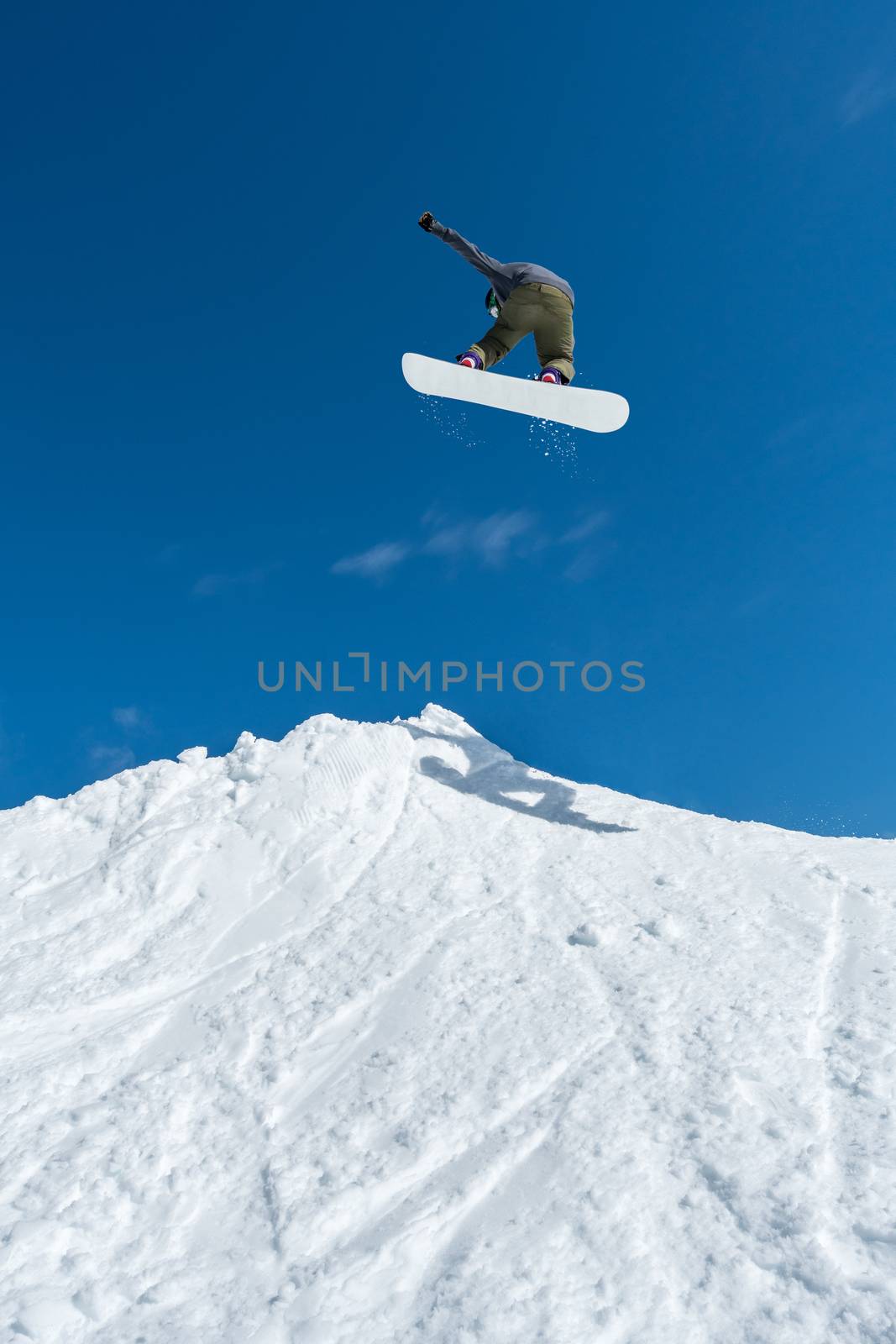 Snowboarder jumping against blue sky by homydesign