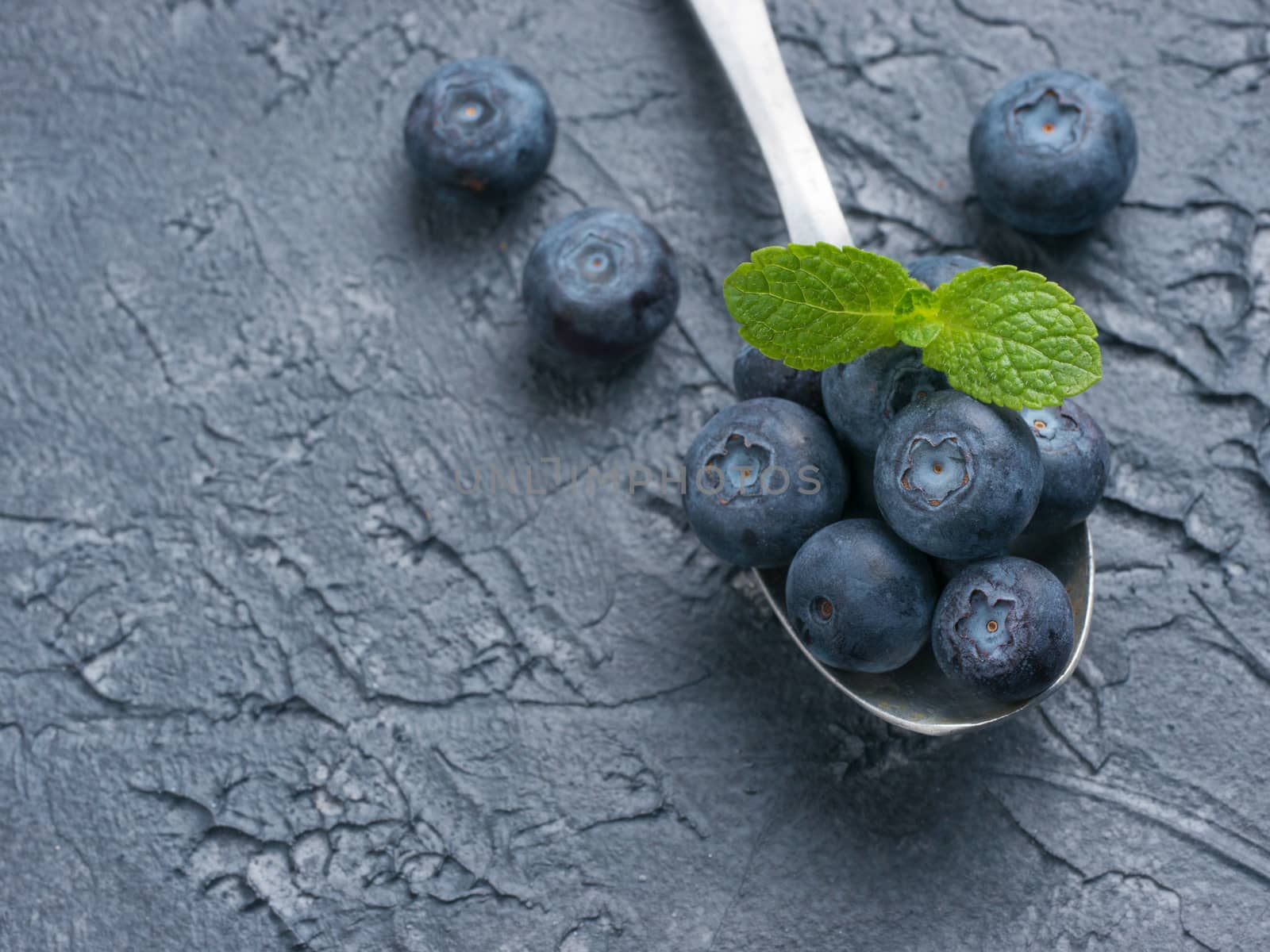 Blueberries in spoon on dark background by fascinadora