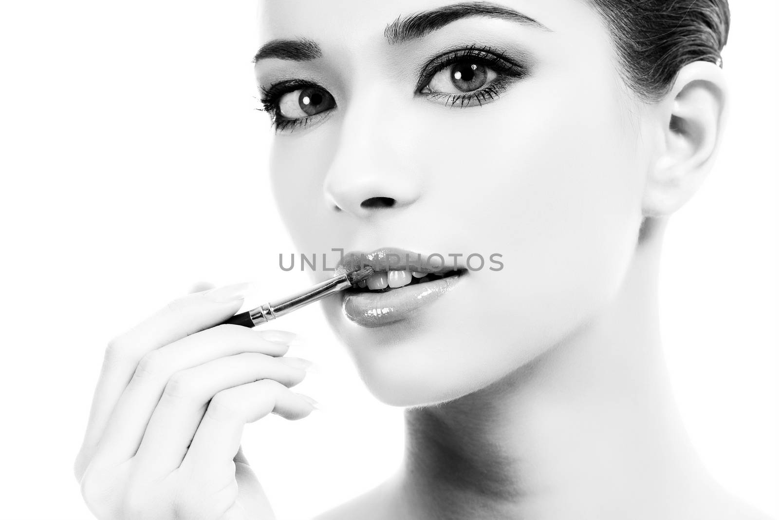 beautiful young woman applying lips makeup with cosmetic brush, white background, copyspace