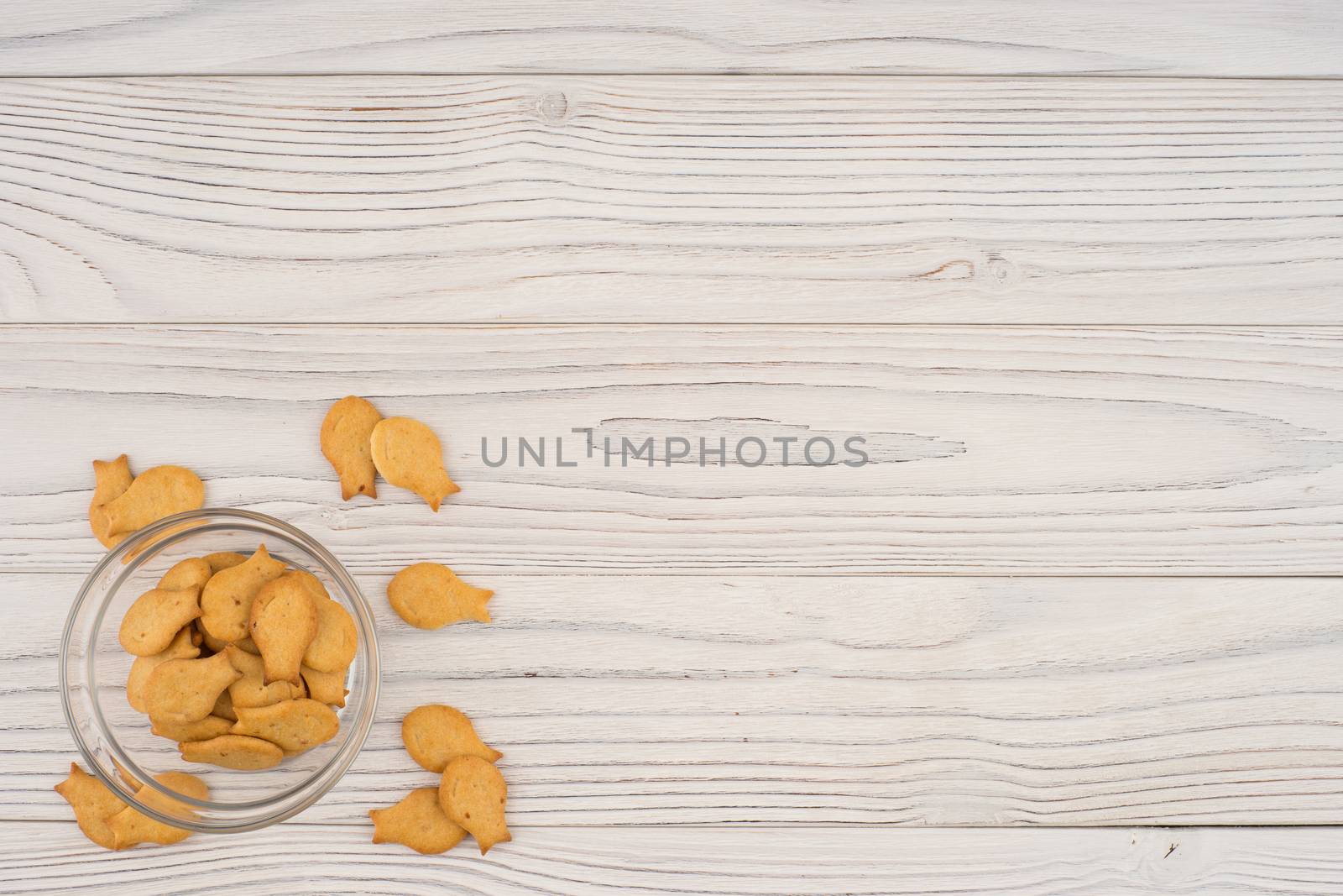Goldfish cracker in a glass bowl on a white wooden table. by DGolbay