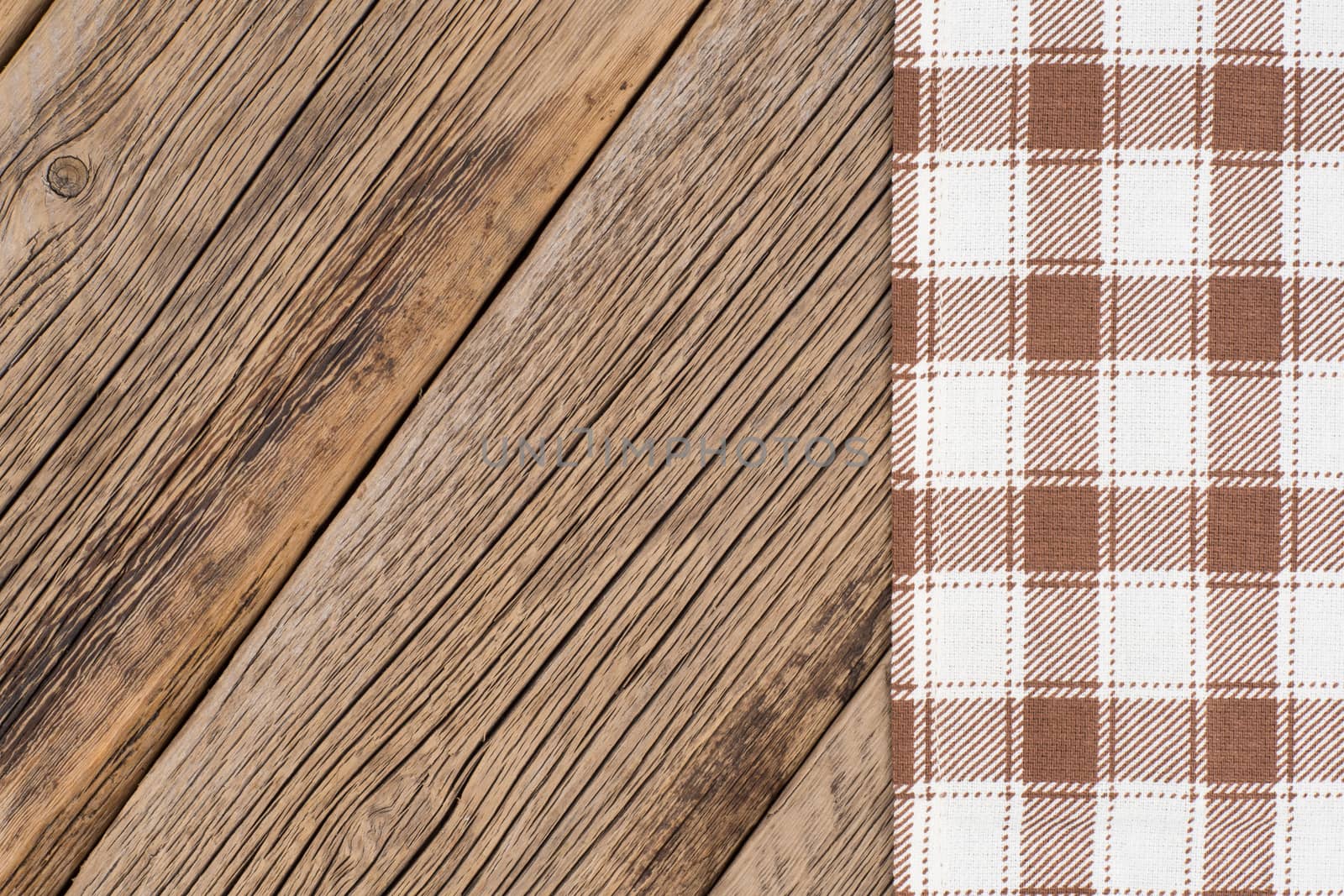 The checkered tablecloth on wooden table. Top view.