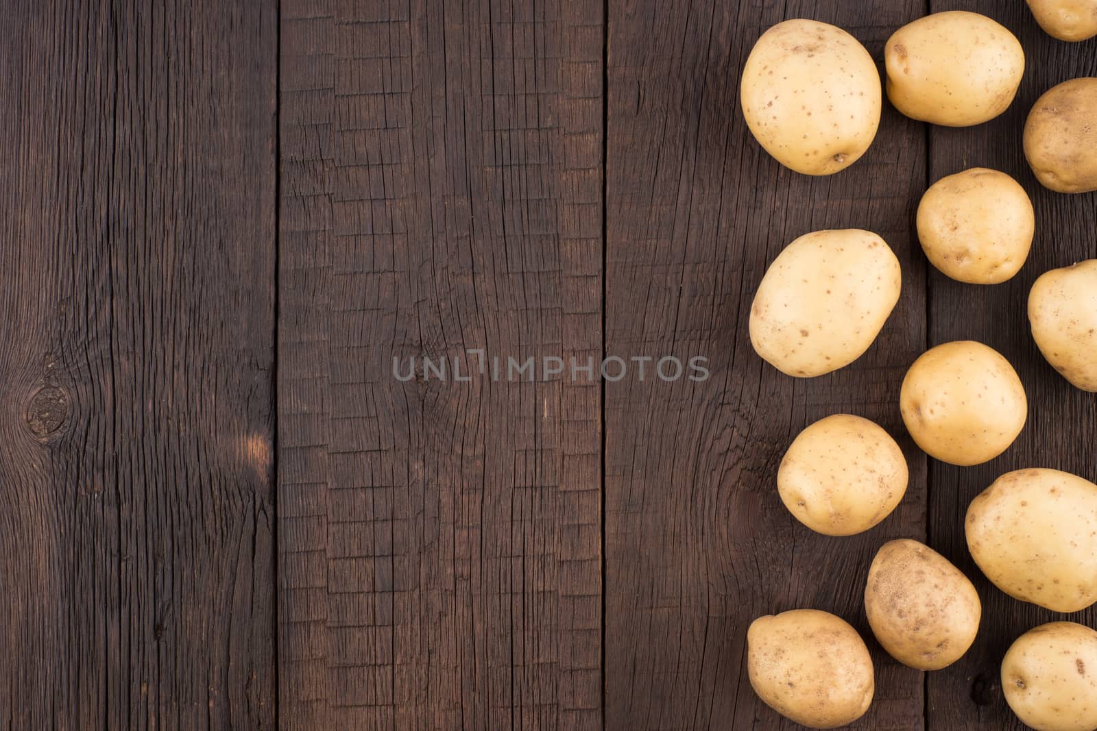 Potatoes on rustic wooden background.  by DGolbay