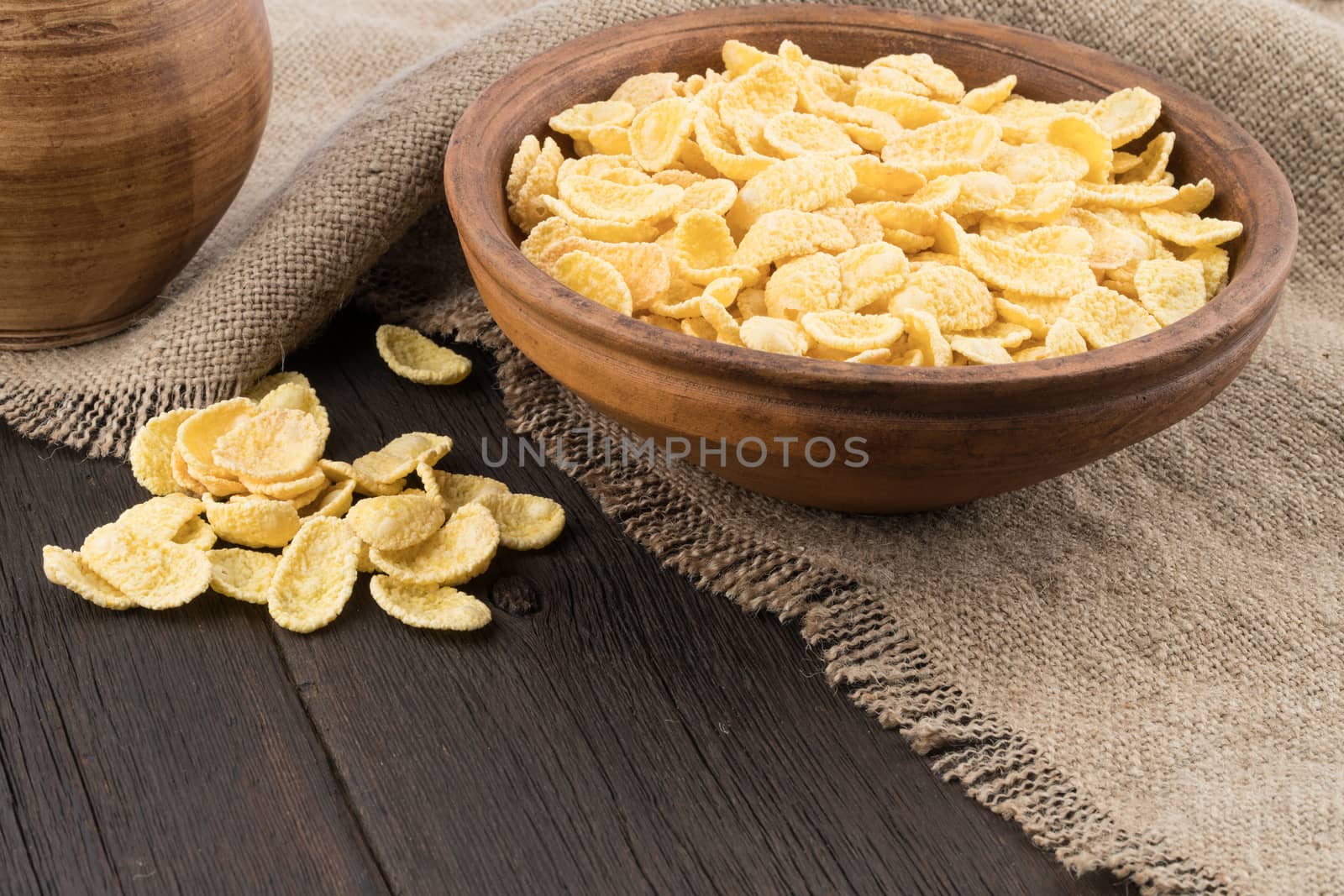 Corn flakes in ceramic bowl on the old wooden table. Selective focus.