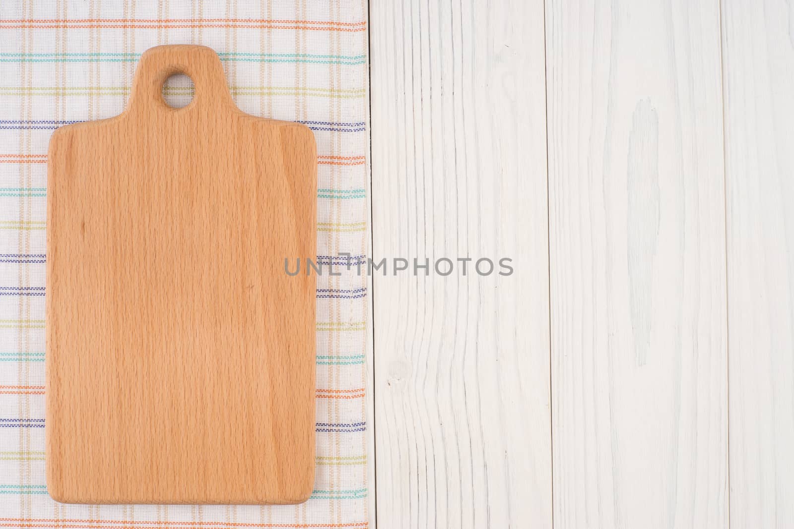 Cutting board on a kitchen napkin on old wooden table. Top view.