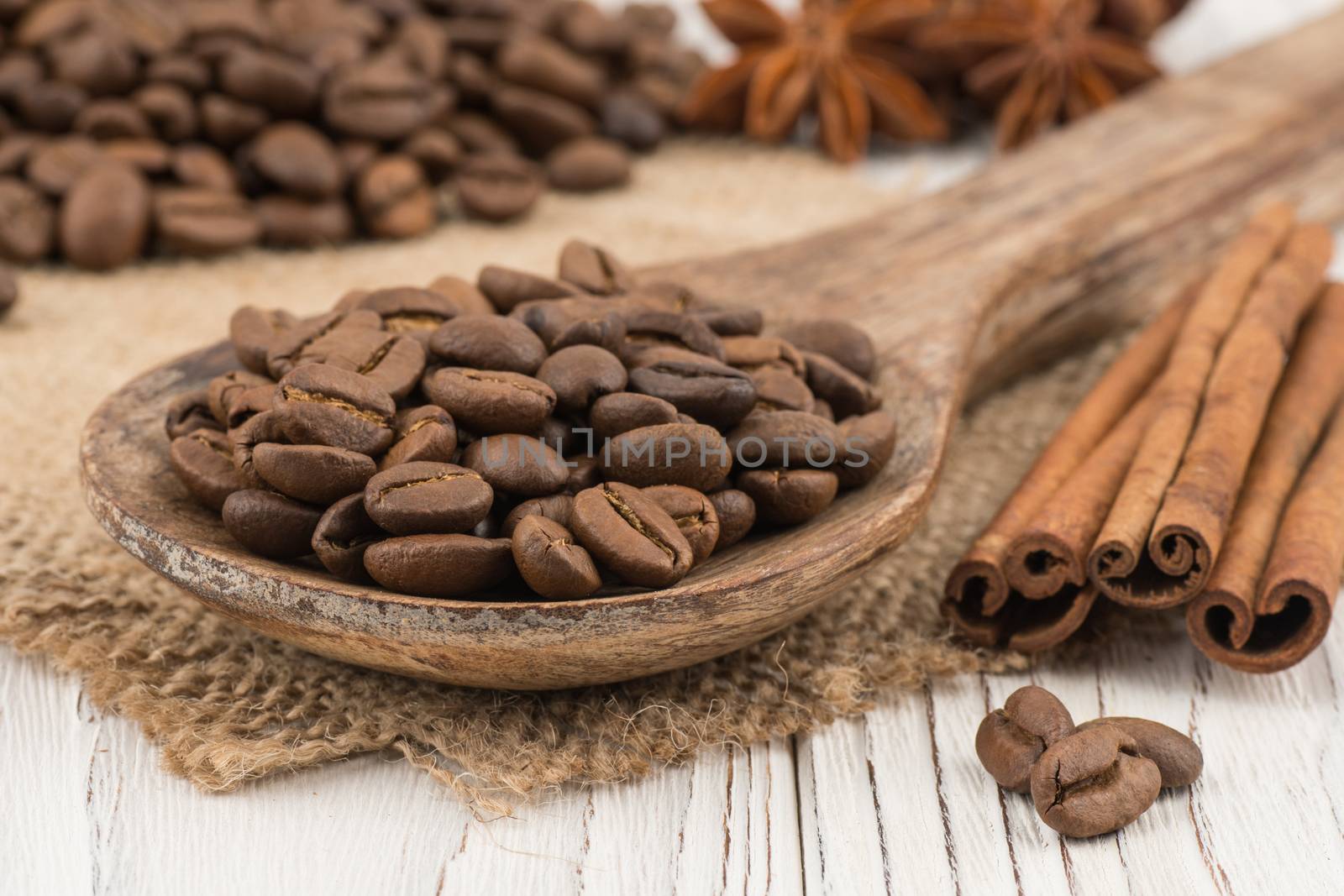 Coffee beans in a wooden spoon on old wooden table. Selective focus. 