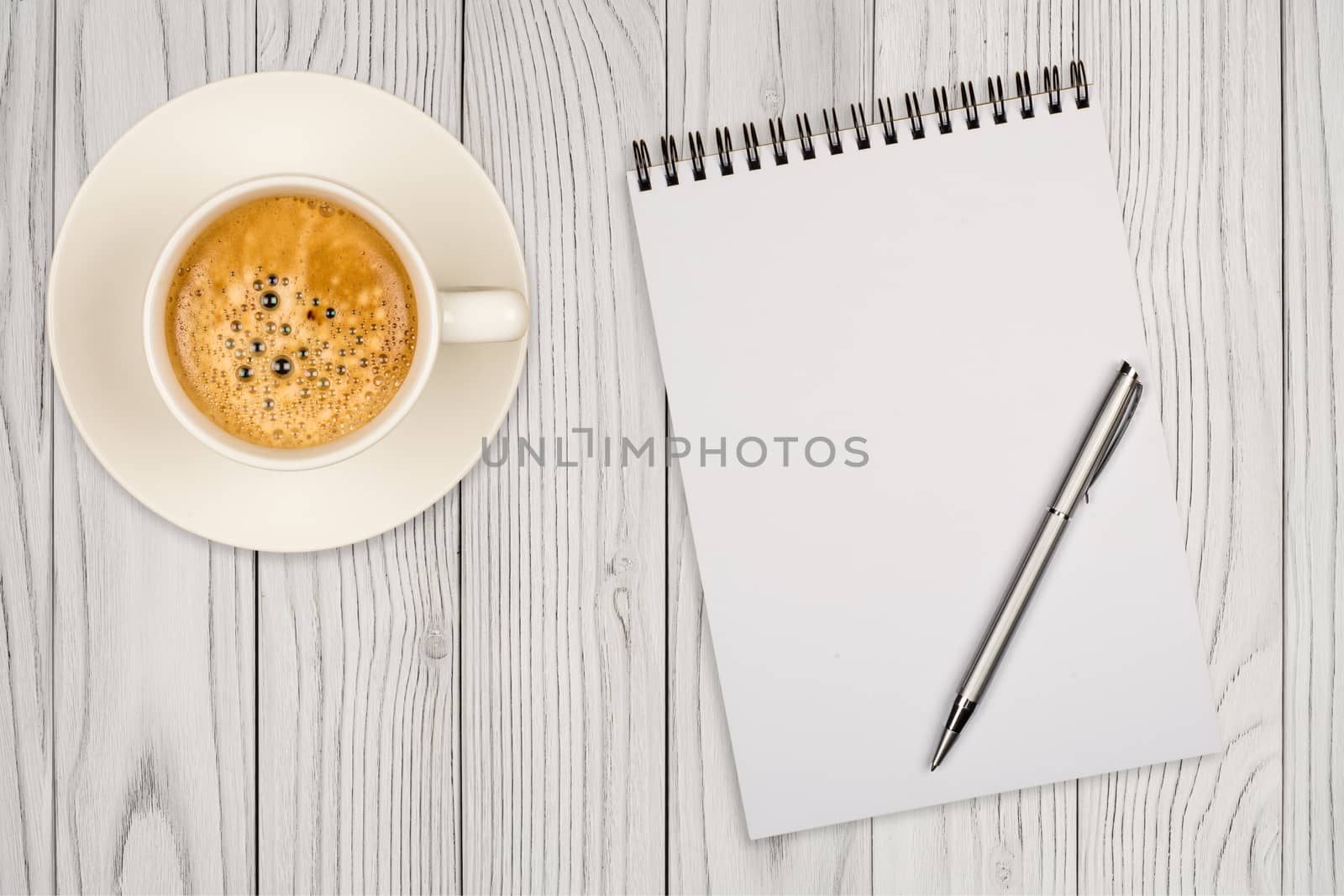 Coffee cup, spiral notebook and pen on the wooden table. Top view.